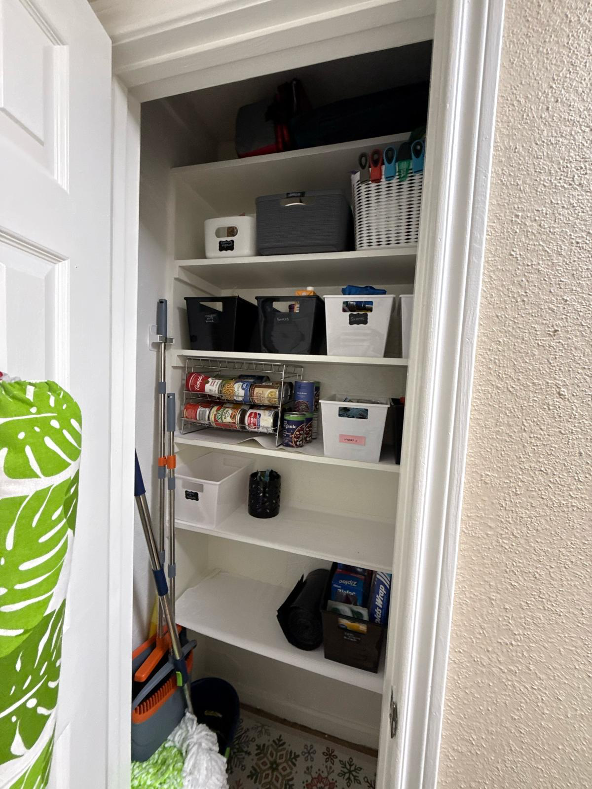 An organized utility closet with labeled bins and supplies